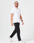 Mann mit Brille trägt nachhaltiges Premium T-Shirt aus 280 GSM Bio-Baumwolle in Weiß mit schwarzer Hose und weißen Sneakern. Nachhaltiges, dickes T-Shirt mit Rundhalsausschnitt, perfekt für moderne Casual Outfits und umweltfreundliche Mode.
